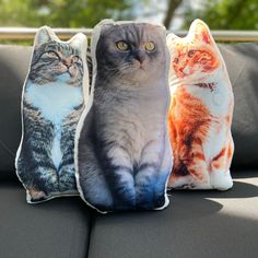 three cat pillows sitting on top of a couch