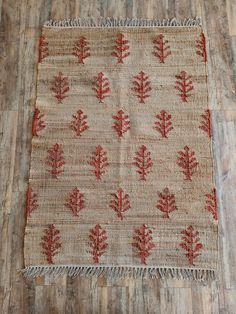 an old rug with red leaves and fringes on top of wood flooring in a room