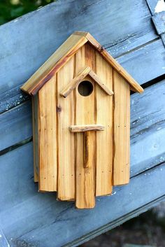 a wooden bird house hanging on the side of a building