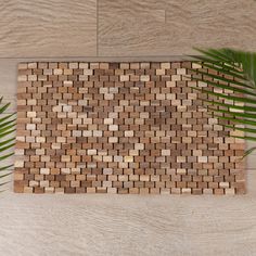 a close up of a mat on a wooden floor with two palm leaves next to it