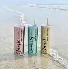 three different colored tumblers sitting on the beach