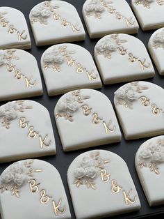 there are many decorated cookies on the baking sheet with gold letters and flowers in them