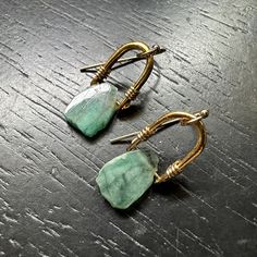 A beautiful Raw Emerald is suspended from one our tiny 24k gold bails with 14K Gold filled wire wraps and earwires. This combo of the bright gold and deep greens looks so great together! We've been up-leveling some 永 designs by adding a thick electroplating of 24K gold over our cast brass medallions- this combo allows for all the beauty and durability of the Gold finish while being much a more affordable option than solid cast gold! Emerald derives it’s glorious green color from the presence of Unique Wire Wrapped Earrings For Everyday, Handmade 14k Gold Green Jewelry, Handmade Green 14k Gold Jewelry, Hand Forged 14k Gold Filled Drop Earrings, Unique Wire Wrapped Everyday Earrings, Hand Forged Green Earrings For Gift, Hand Forged Green Teardrop Jewelry, Everyday Green Brass Jewelry, Everyday Yellow Gold Wire Wrapped Earrings