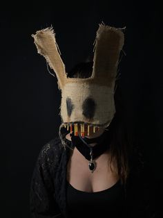 a woman wearing a bunny mask with hair combs in her mouth and black background