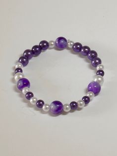 "This is a super fun and colorful handmade beaded bracelet. The \"marbled\" beads give interest and uniqueness for the person who loves to make a statement of color with their jewelry! Very pretty purple/white with \"marbled\" accent beads on a stretchy elastic band. Would fit a 7-7 1/2\" wrist. Picture taken in different lighting to show how it looks under different settings. We offer free shipping on all of our items! If you are interested in a certain color combination, please send me a private message to see if we have your desired colors in stock. Thank you for looking!" Blue And Purple Bracelet, Purple Hand-strung Stretch Bracelet As Gift, Casual Handmade Purple Stretch Bracelet, Handmade Purple Stretch Bracelet, Casual Purple Stretch Bracelet As A Gift, Casual Purple Stretch Bracelet For Gift, Casual Purple Stretch Bracelet As Gift, Casual Purple Stretch Bracelet Gift, Beaded Bracelet Diy