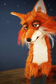 a close up of a stuffed animal on a wooden surface with stars in the background