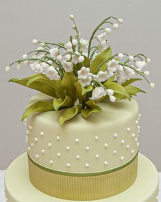 a cake with white flowers and green leaves on top