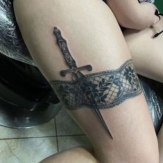 a woman's leg with a tattoo on it and a knife in the middle