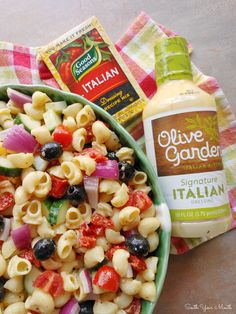 a bowl of pasta salad next to a bottle of olive garden dressing