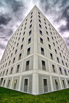 a very tall white building sitting on top of a lush green field under a cloudy sky