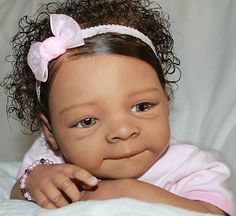 a baby girl with curly hair wearing a pink dress