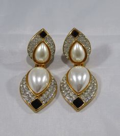 "The past will always return in the fashion world and this piece is back for round two! In the 1920's ladies of class wore the most opulent dresses with jewelry to match. As the years continued, jewelry makers tailored pieces to fashion and trends which resulted in affordability for style. Presenting these Beautiful Vintage Gold Tone Creamy Pearl Cabochon Drop Clip-On Earrings Featuring White Rhinestone Accented Design. Approximate Size: 3.00\" overall length by 1.25\" Wide. Don't forget to LIKE Formal Jeweled Drop Clip-on Earrings, Vintage Jeweled Jewelry For Evening, Glamorous Jeweled Clip-on Earrings For Evening, Glamorous Evening Jeweled Clip-on Earrings, Jeweled Clip-on Earrings For Evening, Elegant Jeweled Clip-on Earrings For Formal Events, Elegant Jeweled Clip-on Earrings For Formal Occasions, Glamorous Jeweled Clip-on Earrings For Formal Events, Vintage Jeweled Clip-on Earrings For Evening