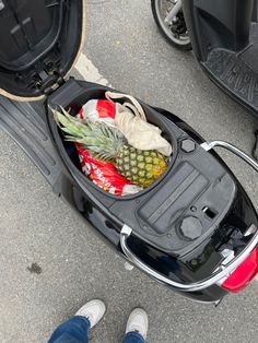 a person standing next to a scooter with a pineapple in the trunk