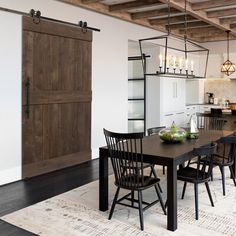 a dining room table and chairs in front of a barn door