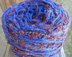 blue and red yarn is sitting on a wooden bench