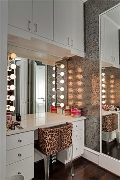 a vanity with lights and stools in front of a mirror that has leopard print on it