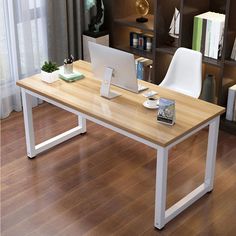 a computer desk with a laptop on it in front of a bookshelf filled with books