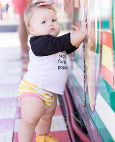 a small child is leaning against a wall and looking at something on the side with her hands