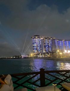 the lights are shining brightly in the night sky over the water and cityscape