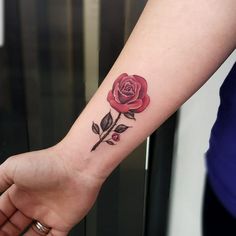 a woman's arm with a rose tattoo on the left side of her wrist