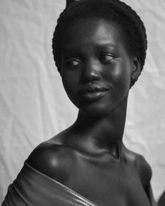 a black and white photo of a woman with dark skin wearing a one shoulder dress