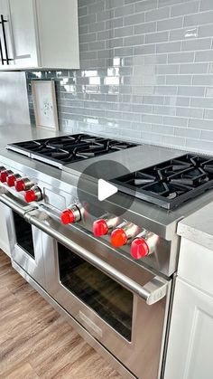 a stove top oven sitting inside of a kitchen next to an oven with red knobs