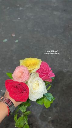 a person's hand holding a bouquet of flowers on the ground with words above it