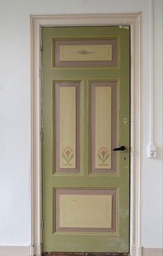 a green door with flowers painted on the front and side panels, in an empty room