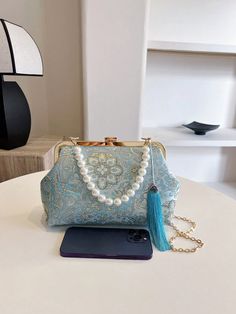 Add an elegant touch to any evening outfit with our Pearl-Adorned Blue Embroidered Handbag. The perfect accessory for parties and special occasions, this handbag features beautiful pearl embellishments and intricate embroidery. Elevate your style and make a statement with this ultimate evening accessory. Color : Blue Bag Size : Medium Pattern Type : Plants Type : Kiss Lock Bag Material : Fabric Composition : 100% Polyester Bag Height Bag Length Bag Width 17 25 8 Blue Embroidered Clutch Shoulder Bag, Blue Shoulder Bag With Detachable Handle For Party, Embroidered Handheld Shoulder Bag For Evening, Floral Embroidered Evening Bags, Embroidered Shoulder Bag For Party, Elegant Blue Shoulder Bag For Events, Evening Handheld Shoulder Bag With Floral Embroidery, Blue Embroidered Evening Bag, Blue Embroidered Shoulder Bag For Party