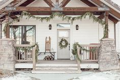 a white house decorated for christmas with wreaths on the front porch