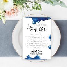 a place setting with flowers and a thank you card on the plate next to it