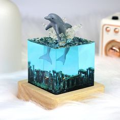 two dolphins are jumping out of the water in a cube shaped box on a white furnishing