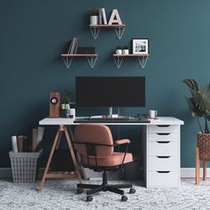 an office desk with a computer on it in front of a wall painted teal