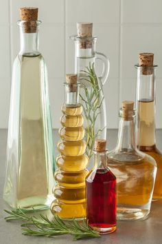 three different types of olive oil in glass bottles with rosemary sprigs on the side