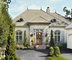 a white house with lots of trees and bushes around it's front entrance area