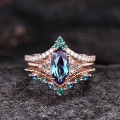 an image of a ring with blue and green stones on it, sitting on top of a rock