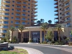 an apartment building with palm trees in front of it and a one sign above the entrance