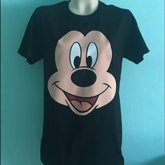 a mickey mouse t - shirt hanging on a mannequin's head with a blue wall in the background