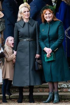 two women standing next to each other in front of a group of people wearing coats and hats