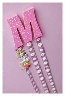 three pink and white wooden letters on top of each other, with flowers in the middle