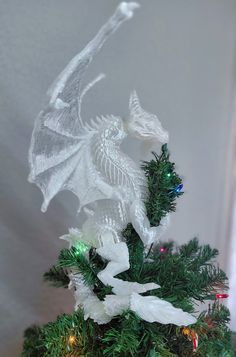 a white dragon on top of a christmas tree with lights in its mouth and wings