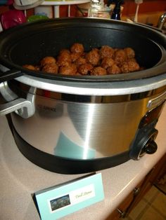 a large pot filled with meatballs sitting on top of a counter next to a card