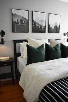 a bed with green and white pillows in a bedroom next to two framed pictures on the wall