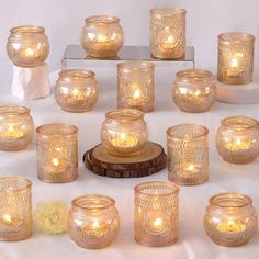 there are many glass jars with candles in them on the table next to each other