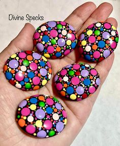 four colorful dots painted on rocks in someone's hand