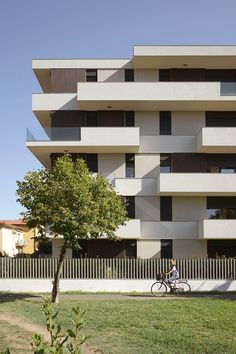 a person riding a bike in front of a tall white building with balconies