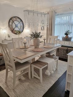 a dining room table and chairs with a clock on the wall