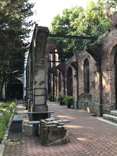 an old brick building with benches and trees