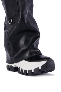 The AZALEA WANG Ezrah Black Boot is a flatform sneaker boot hybrid featuring a faux leather upper, a fold-over knee-high shaft, a belted design, and a slightly covered platform rubber lug sole. Complete with functional cargo side pockets, a pull-on fit, and silver metallic hardware accents. (all measurements approximate from a size 7.5) - DenimTextile Upper - Square Toe - Flatform Wedge Sole - 16” Shaft Height - 19” Shaft Opening Circumference - 13” Calf Circumference  - 2.25” Flatform Sole Height - 3” Chunky Heel Height - Imported Product ID: 387462 Flatform Sneakers, Azalea Wang, Lug Sole, Chunky Heel, Chunky Heels, Black Boots, Knee High, Sneaker Boots, Metallic Silver