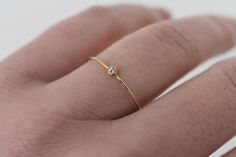 a woman's hand with a gold ring on it and a diamond in the middle